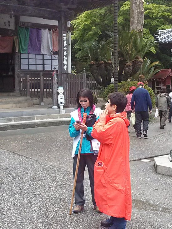切幡寺の本堂前でスマホで写真を撮るメンバー。雨が降ったりやんだりで服装もバラバラ!!