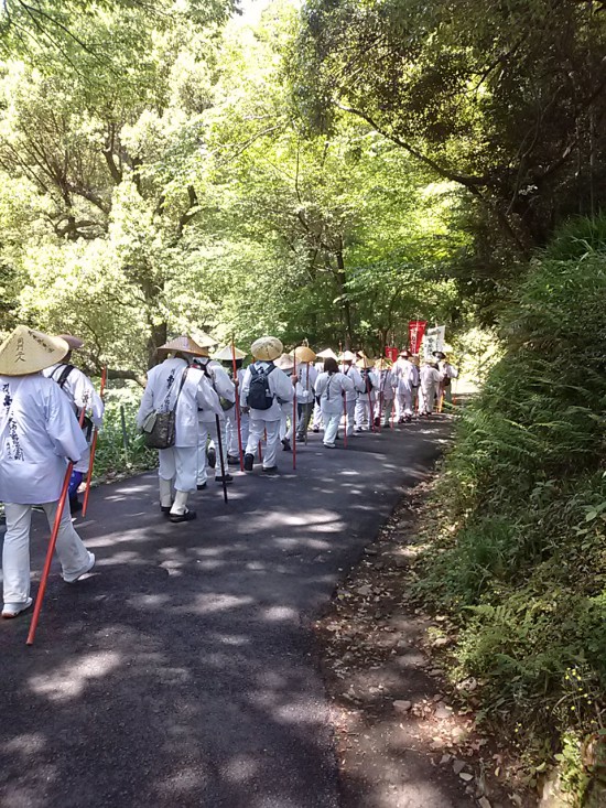 大きなお大師さまの前の坂を一列で下っています。さきほどの本堂のお寺です。もうおわかりですね!?